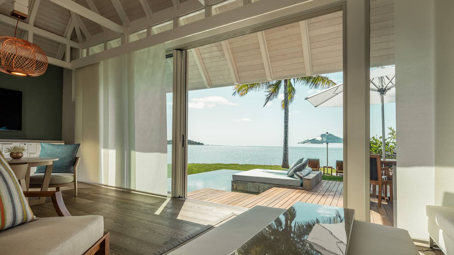 Sanctuary Beach Pool Villa lamp over table by white curtain, open wall to patio, pool