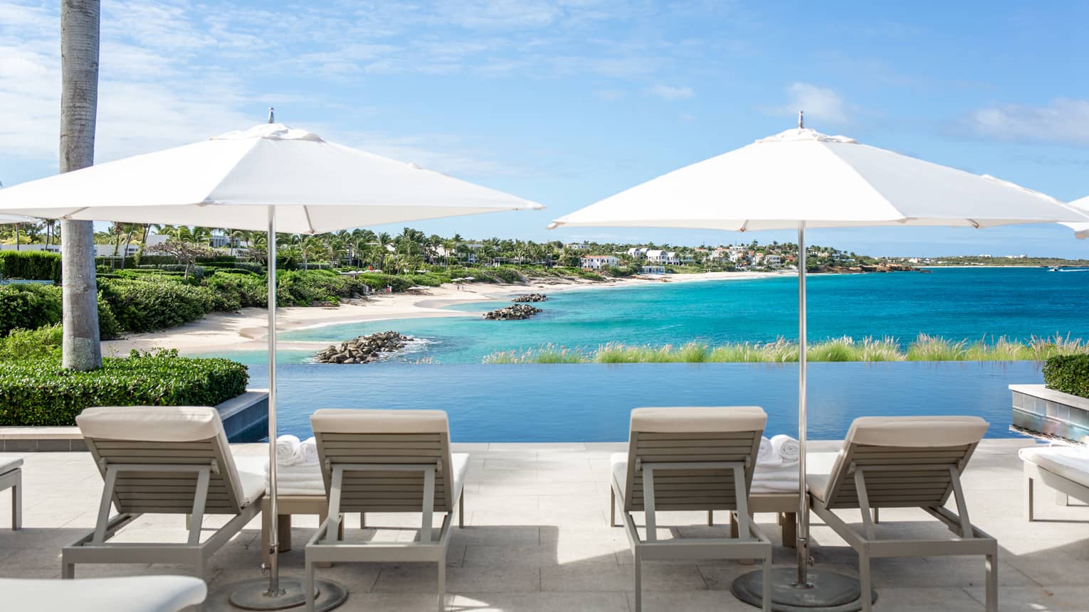 Lounge chairs and umbrellas looking out at a beach shore.