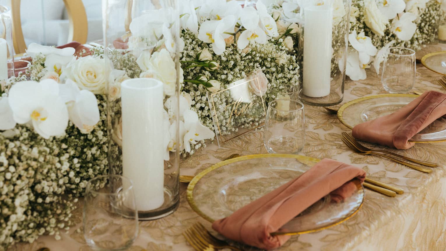A large table with flower arrangements and candles along the center.