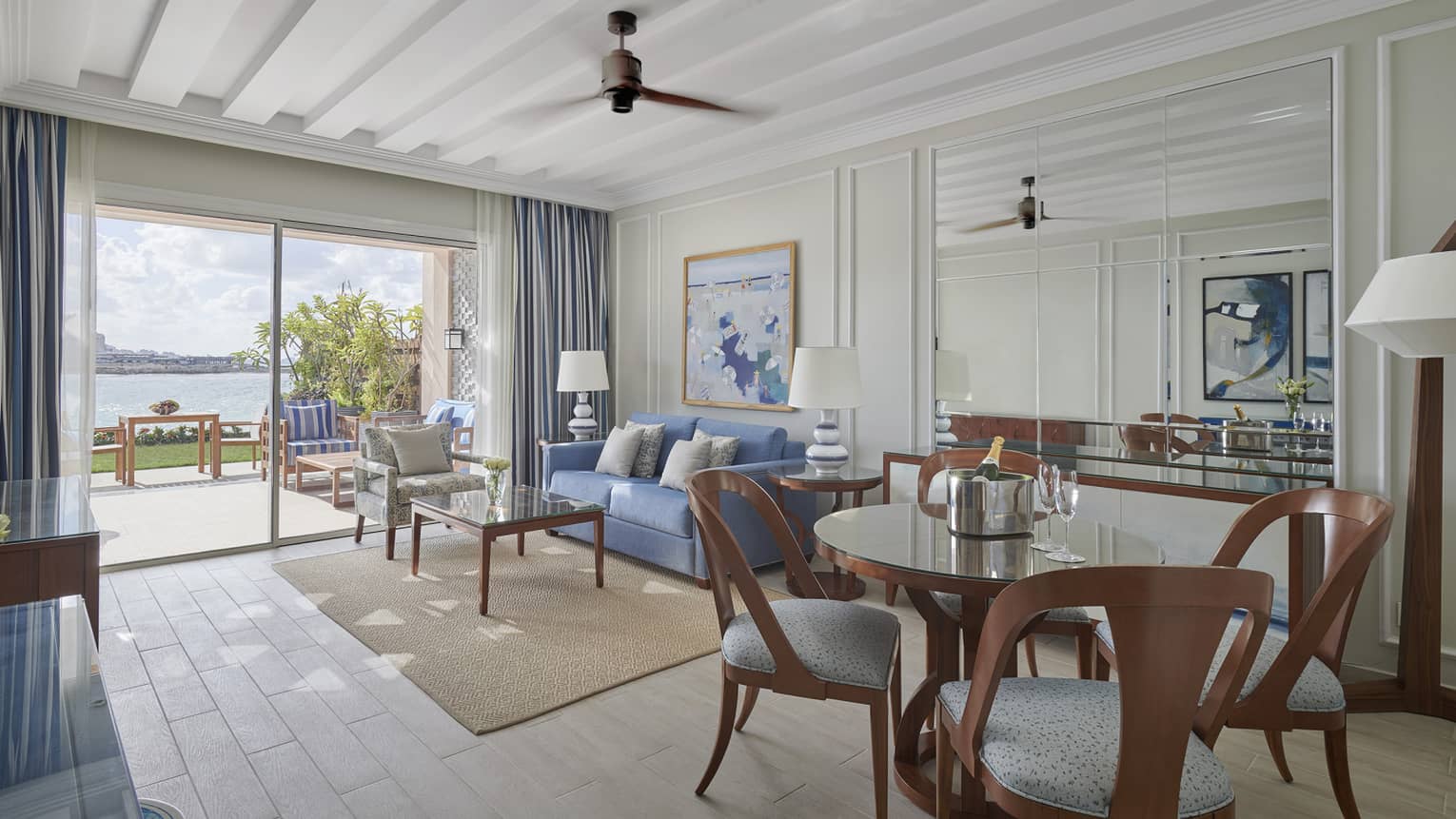 Living area with round dining table, blue sofa, white wooden ceiling, walk-out patio