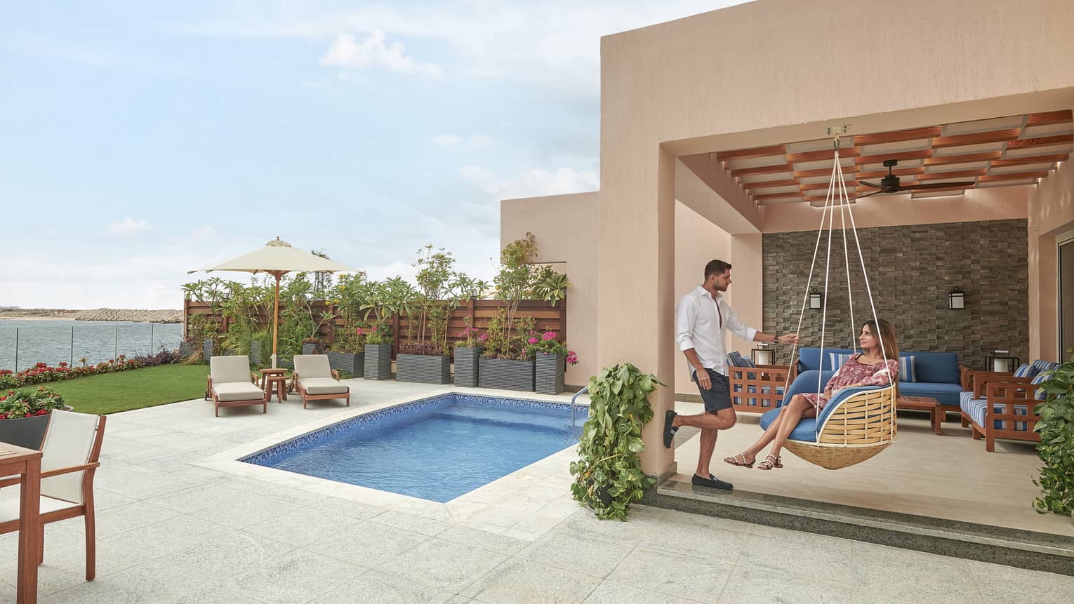Woman sits in a hanging lounge chair on pool terrace
