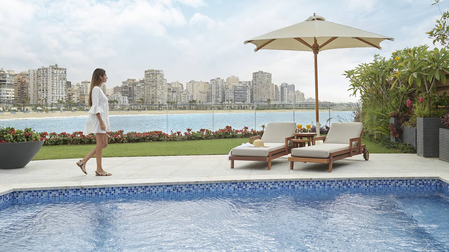 A women walking to a poolside cabana overlooking the city skyline