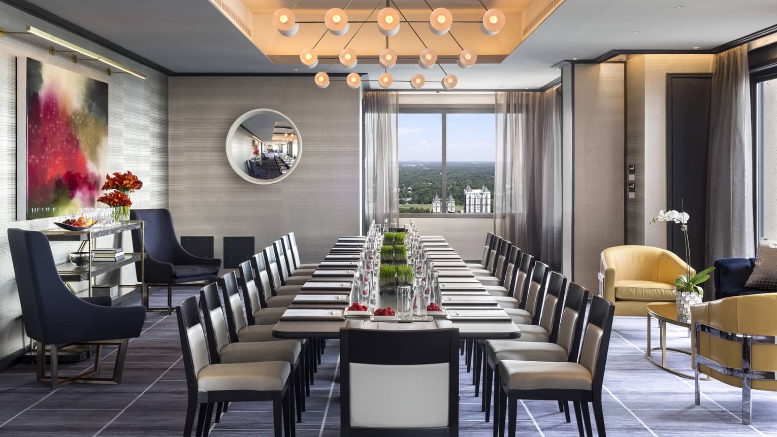 A modern light fixture hangs over a long, set table