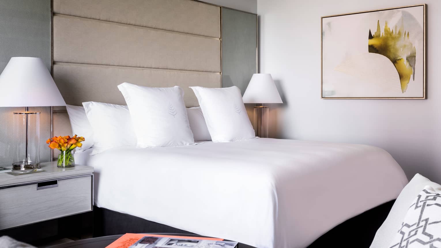 Midtown Premier Room white bed, linens in front of tall padded headboard, framed abstract art on wall