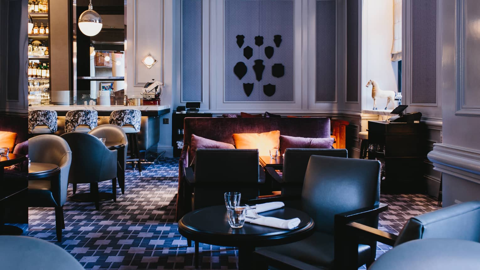Leather chairs, cocktail tables, sofa with pillows in Bar Margot lounge 