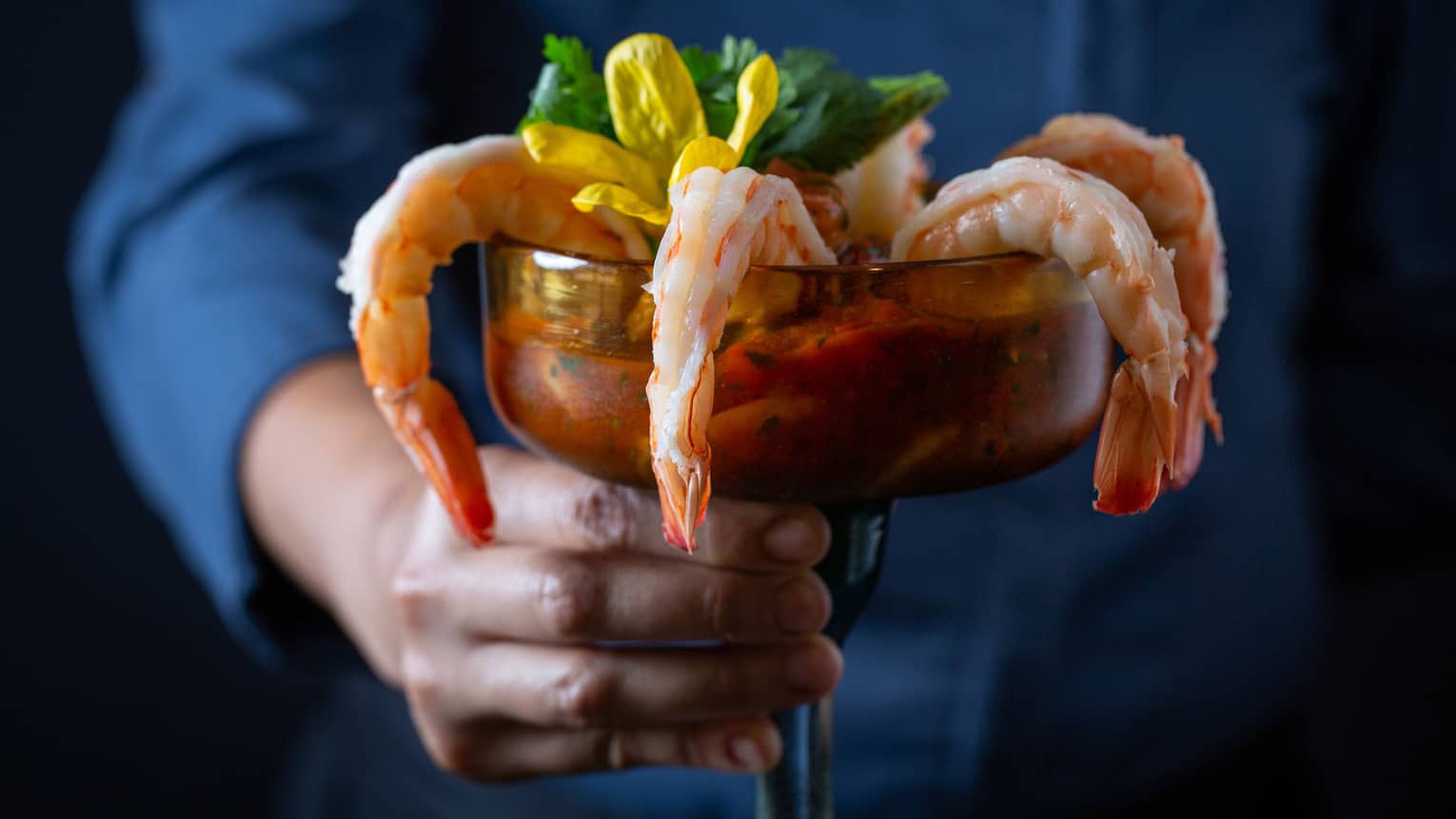 A hand holding cocktail shrimp designed to look like a cocktail drink.