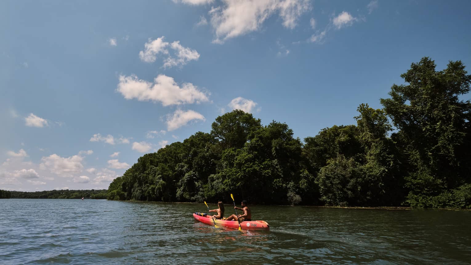 Two guests on a kayak using oars to move the kayak through the water