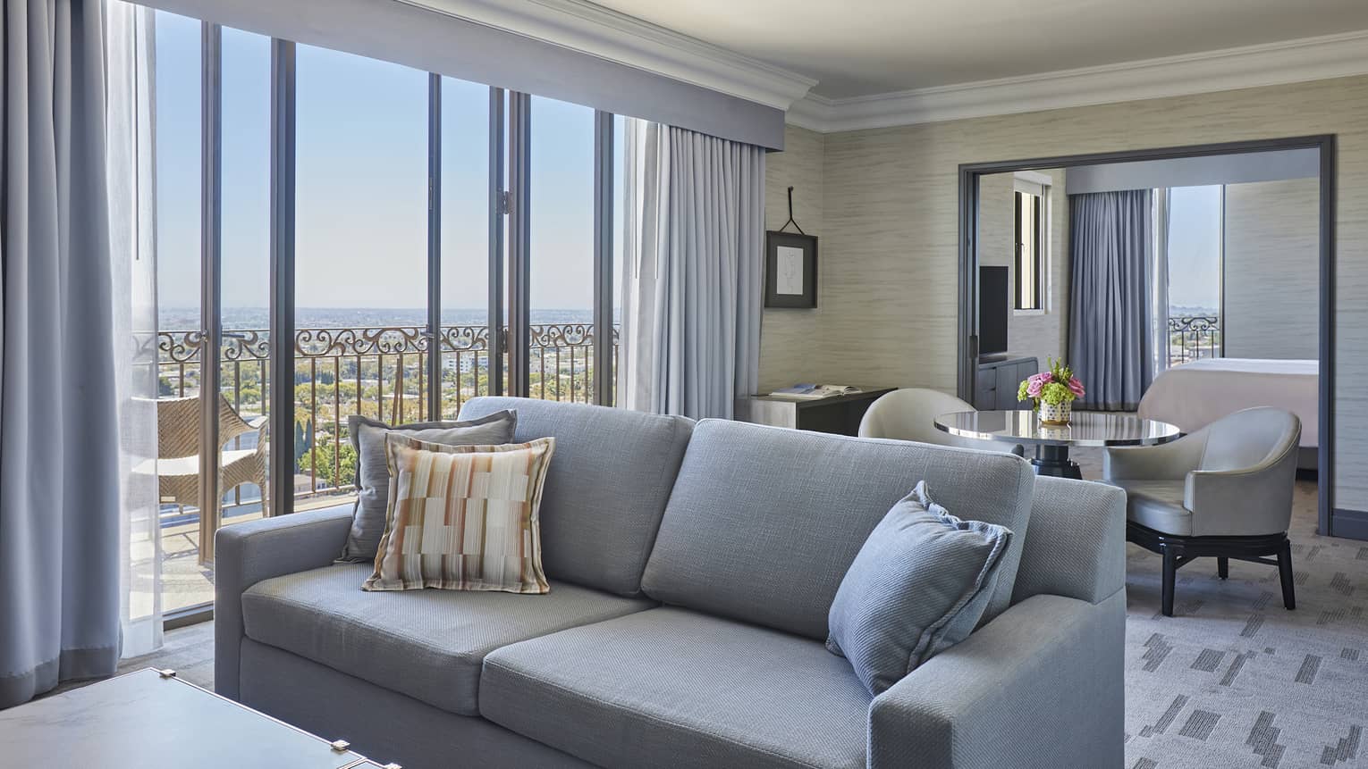 Grey sofa with small table and two chairs behind it, walk-out balcony