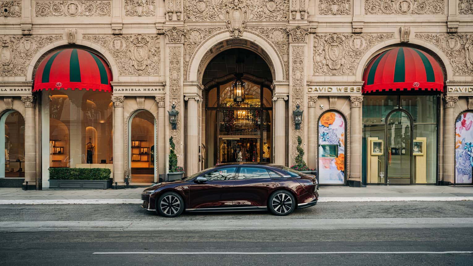 A hotel car parked outside of a building with arched doorways and flags