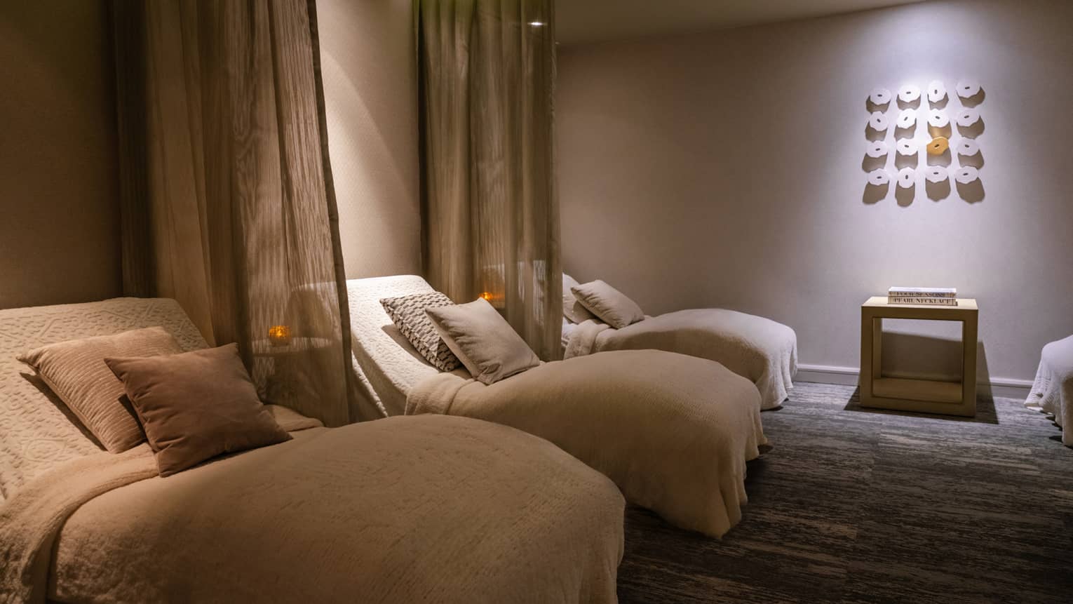 Spa beds in a room with curtains and wall art