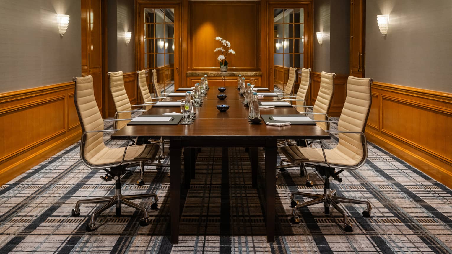 A meeting room with a patterned floor and a bouquet of flowers at the end of the table