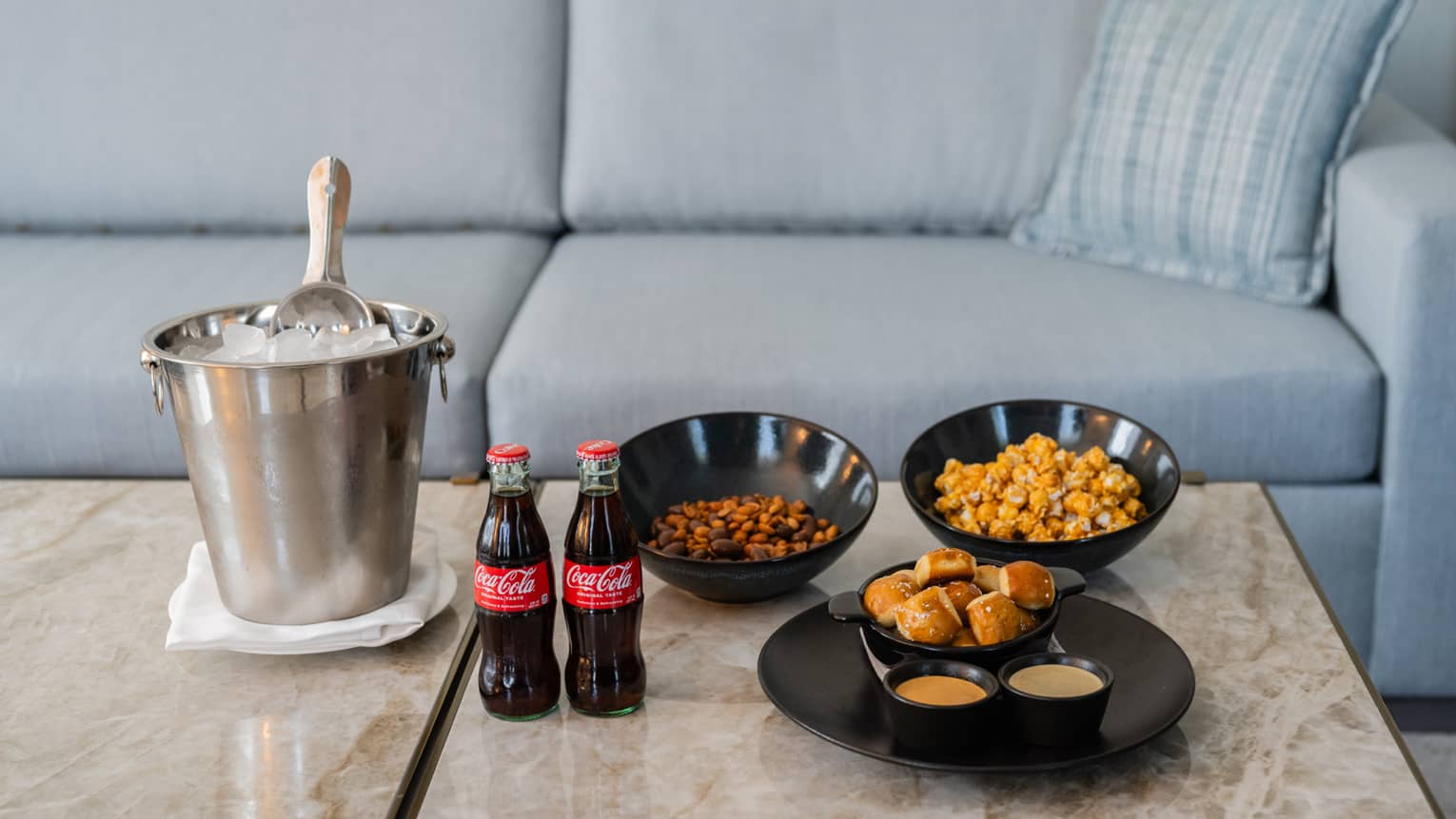 A bucket of ice with soda and bowls of snacks