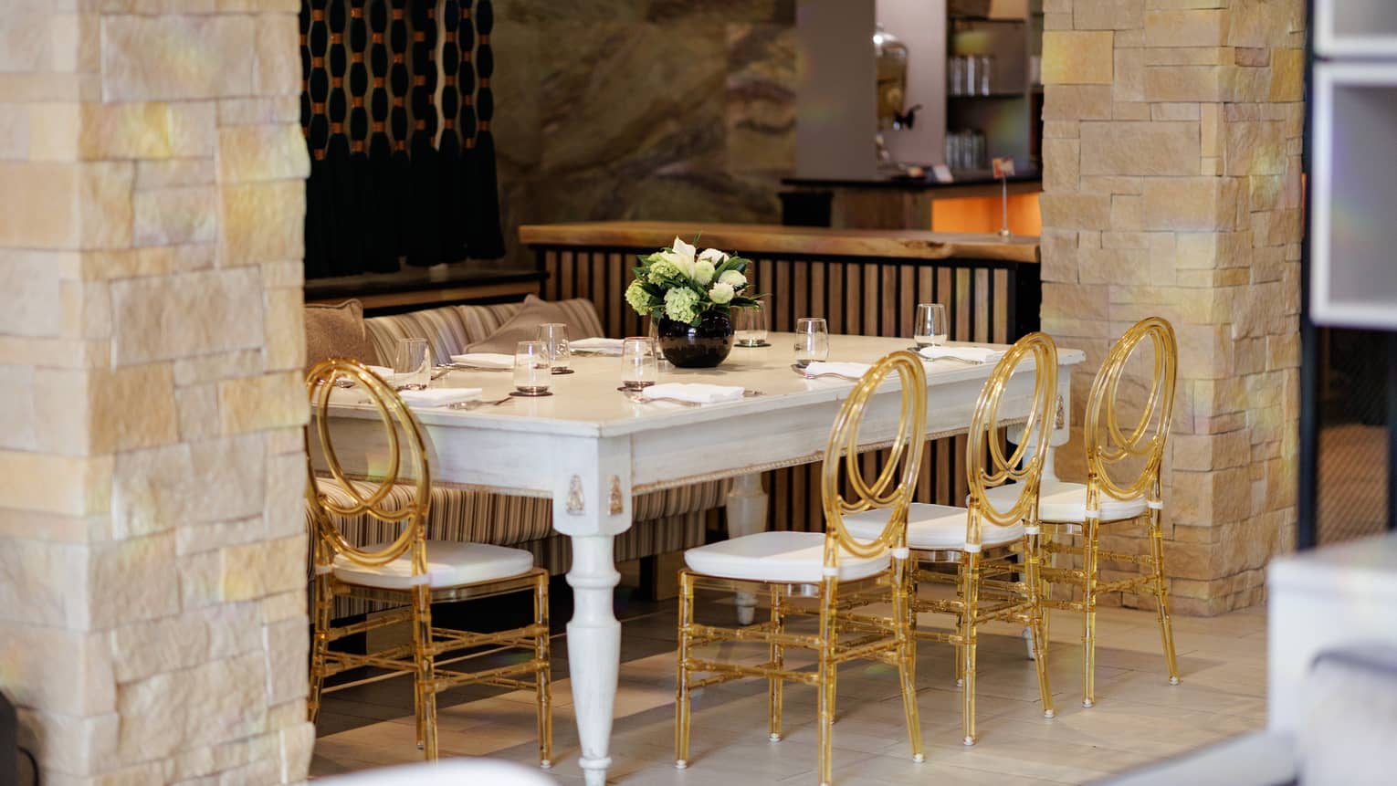 White rectangular table with a bench on one side and four gold-and-white chairs on the other side