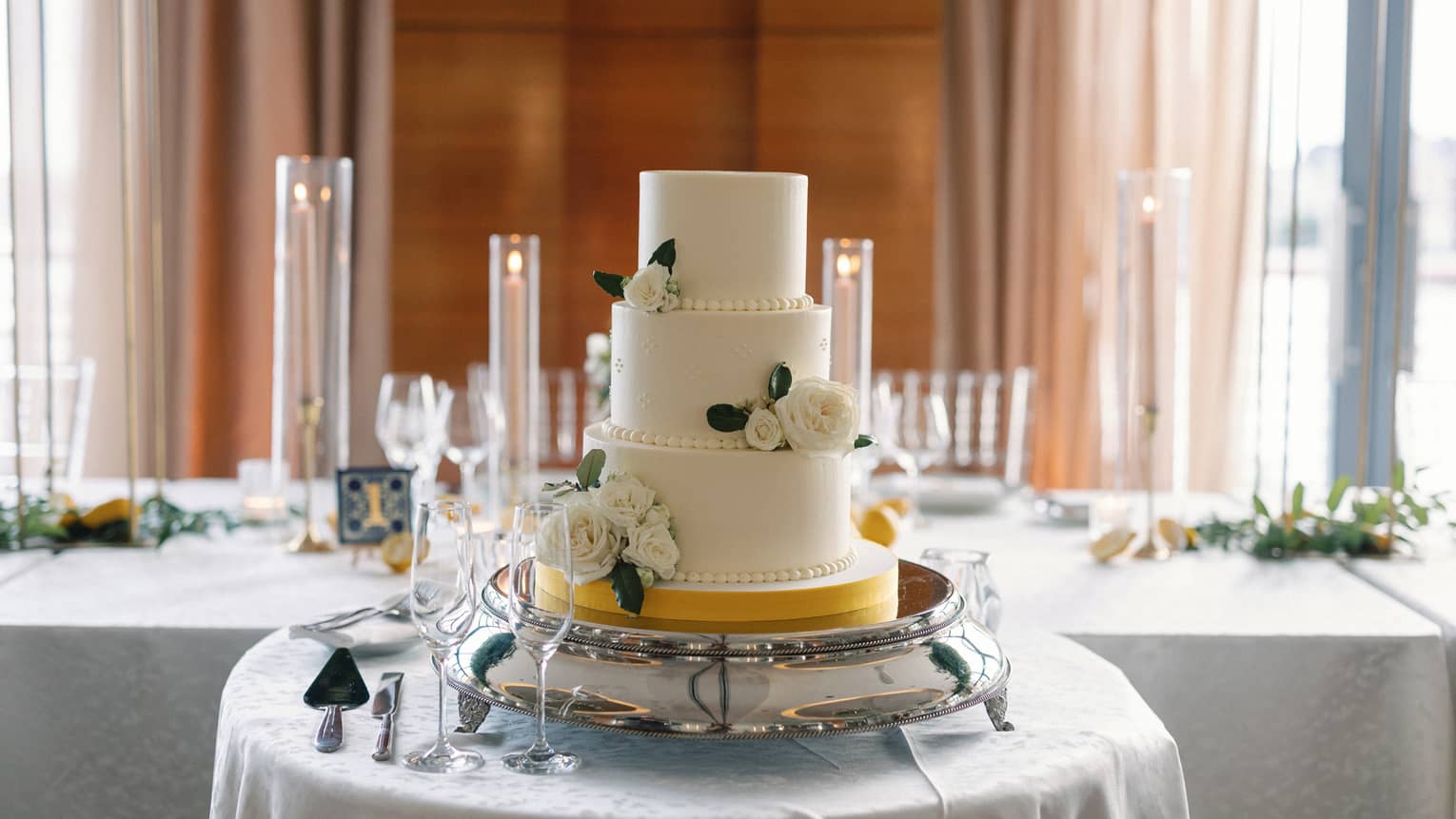 A three-layer wedding cake with flowers on a circular table