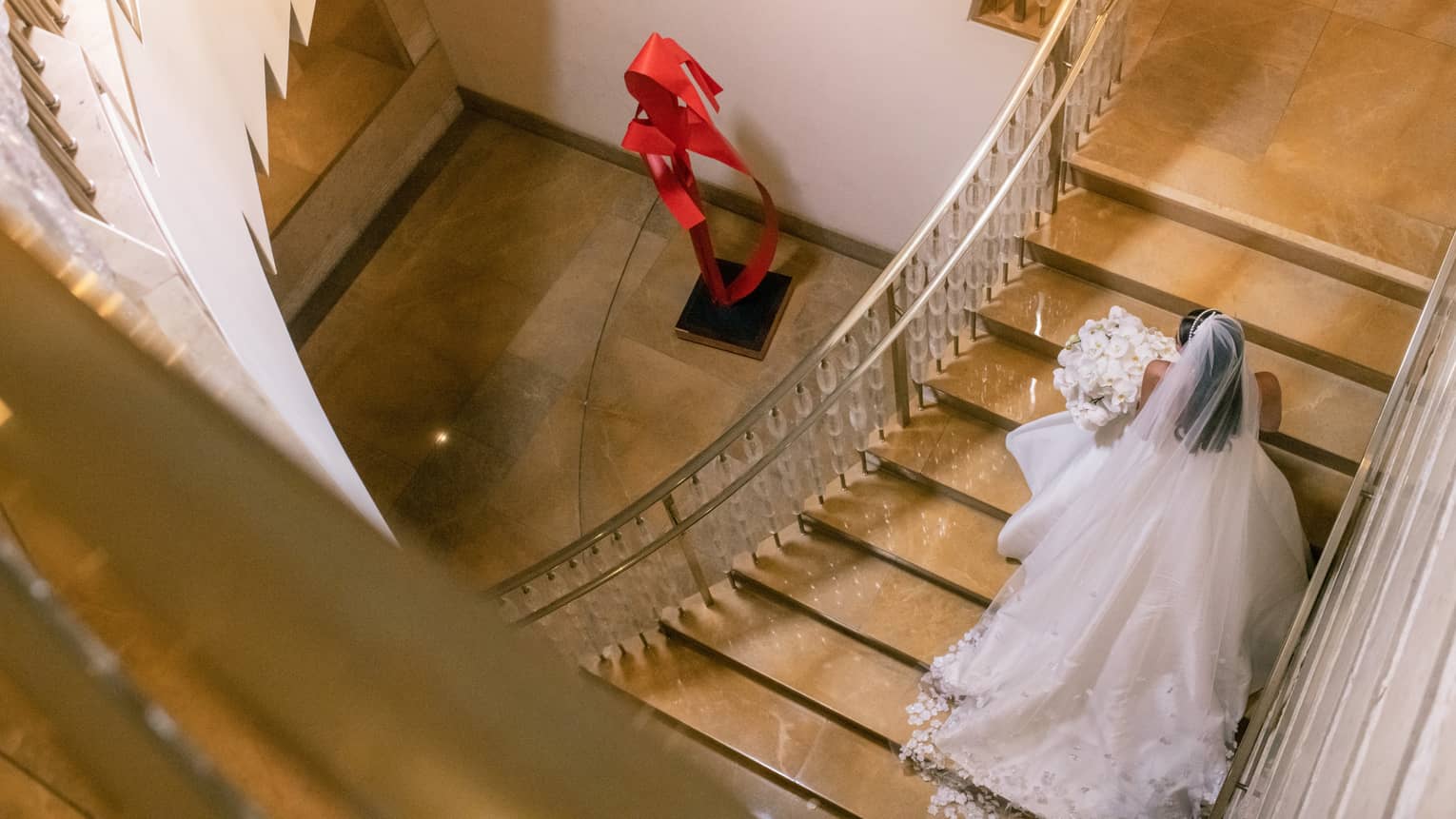 A person wearing a wedding dress and holding a bouquet of flowers while walking up stairs
