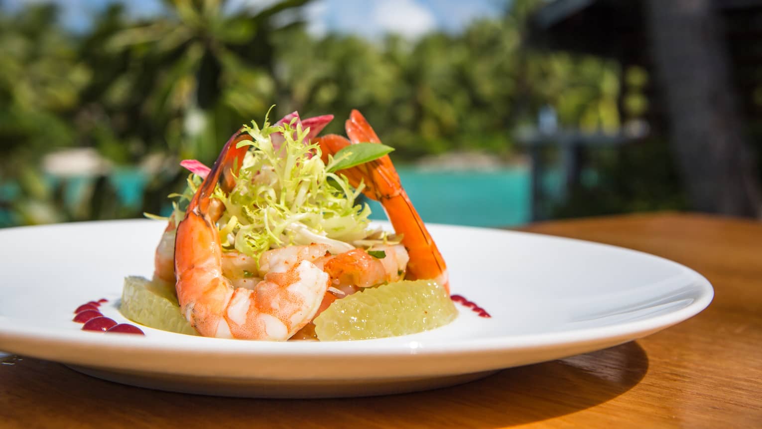 Patio table, salad plate with large shrimp on fresh greens and fruit