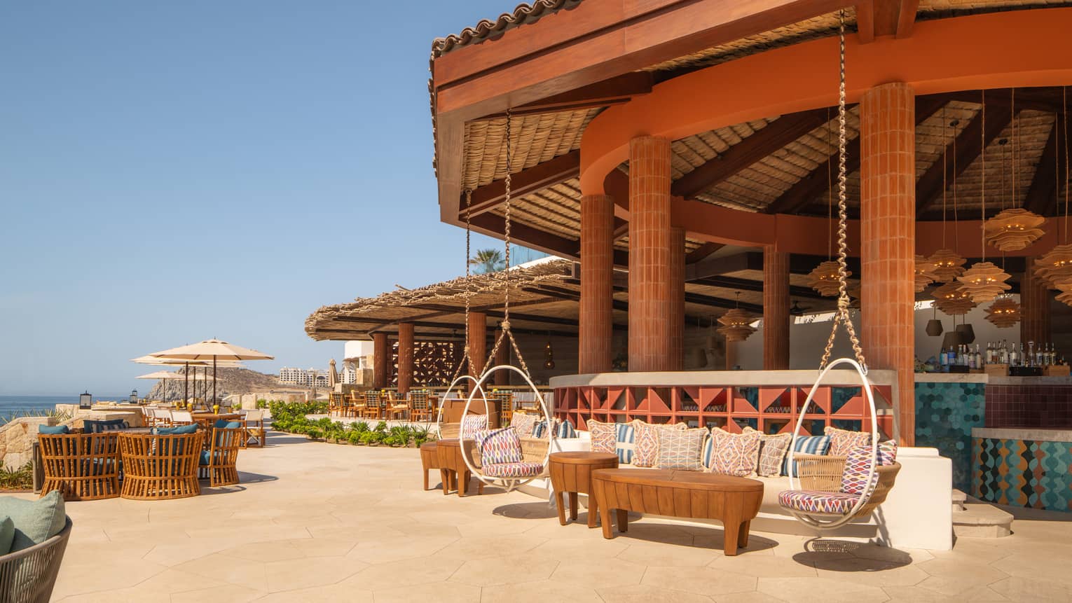 Open-air terrace with various seating areas including bench seating, coffee tables and swinging egg-shaped chairs