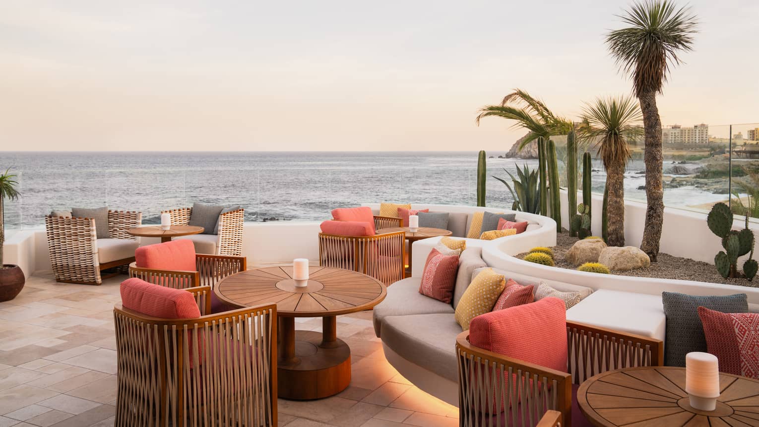 Open-air rooftop bar with curved bench seating along one wall and rattan tables and chairs