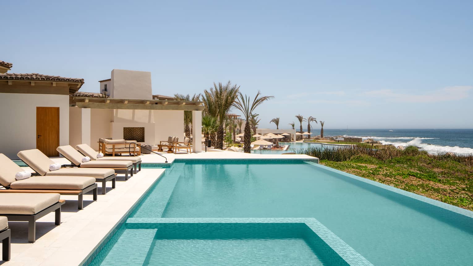 Large pool and sun loungers on a private villa terrace overlooking the sea