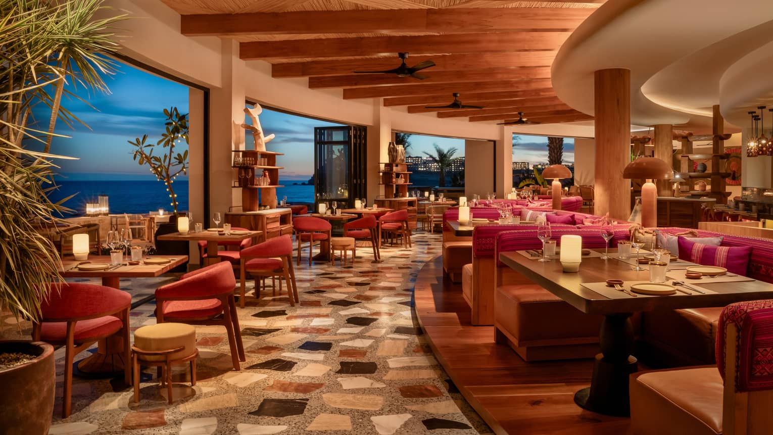 Interior, curved edge of resort restaurant with indoor-outdoor seating and ocean view