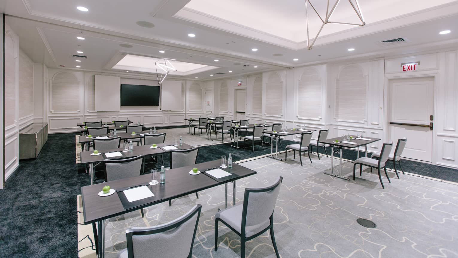 A large meeting room with desks and chairs in rows.