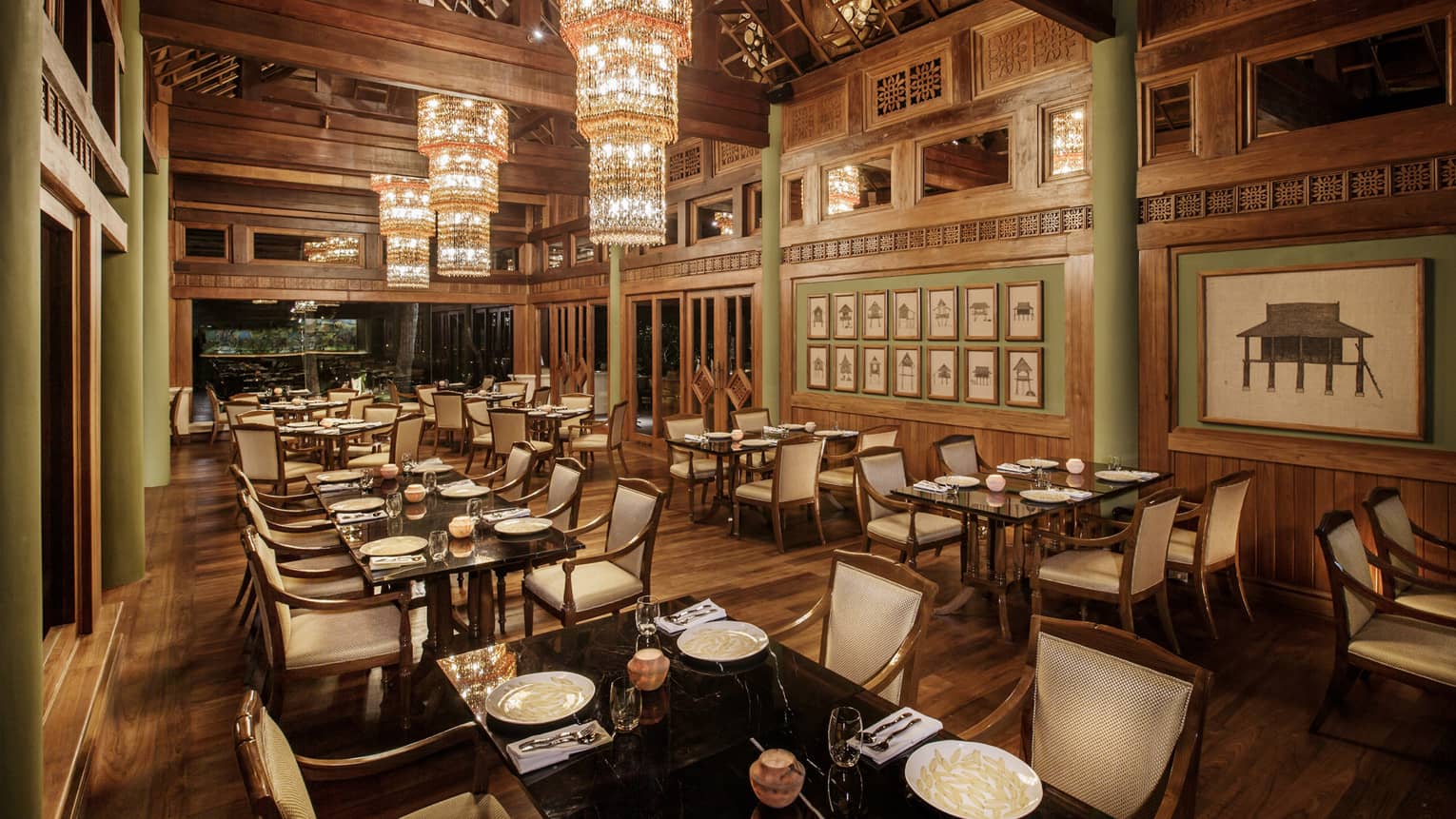 Long crystal chandeliers hang from high ceilings over KHAO indoor dining room with wood decor