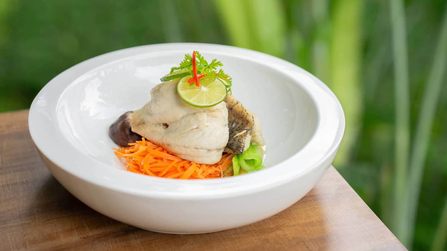 Steamed Gulf of Thailand Sea Bass with Lime and Garlic in white bowl