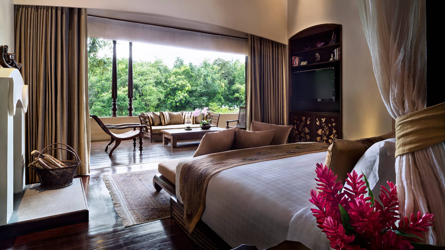 Residence Villa bed from behind canopy, curtains along open wall to balcony with loveseat, chairs