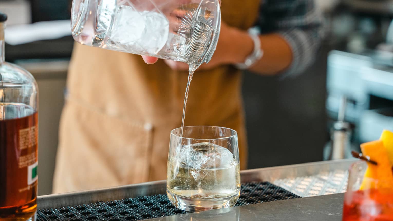 Bartender pours cocktail through strainer