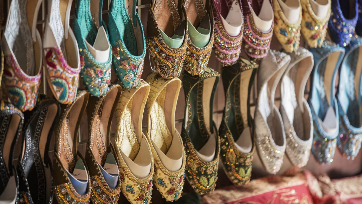 Rows of colourful shoes with beadwork and embroidery hang from market wall