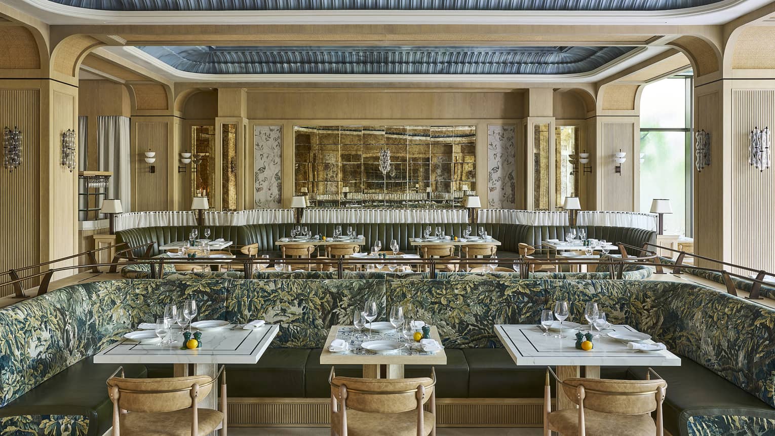 Bright, open restaurant space with neutral-coloured walls, decorative recessed ceilings, natural light, and tables and chairs and banquette seating