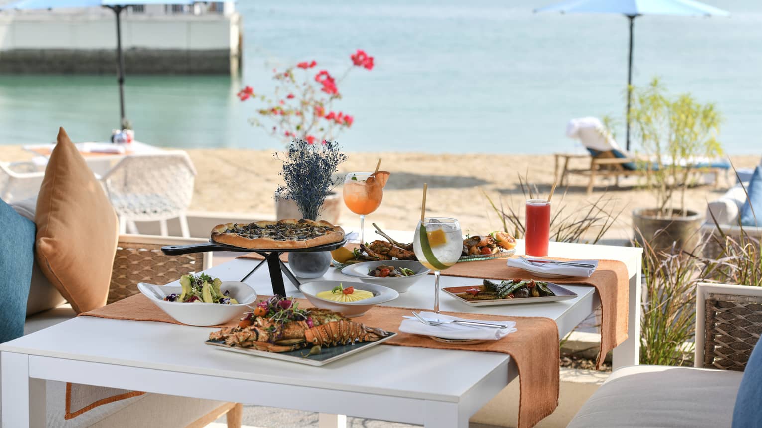 A white outdoor table set for four next to the beach