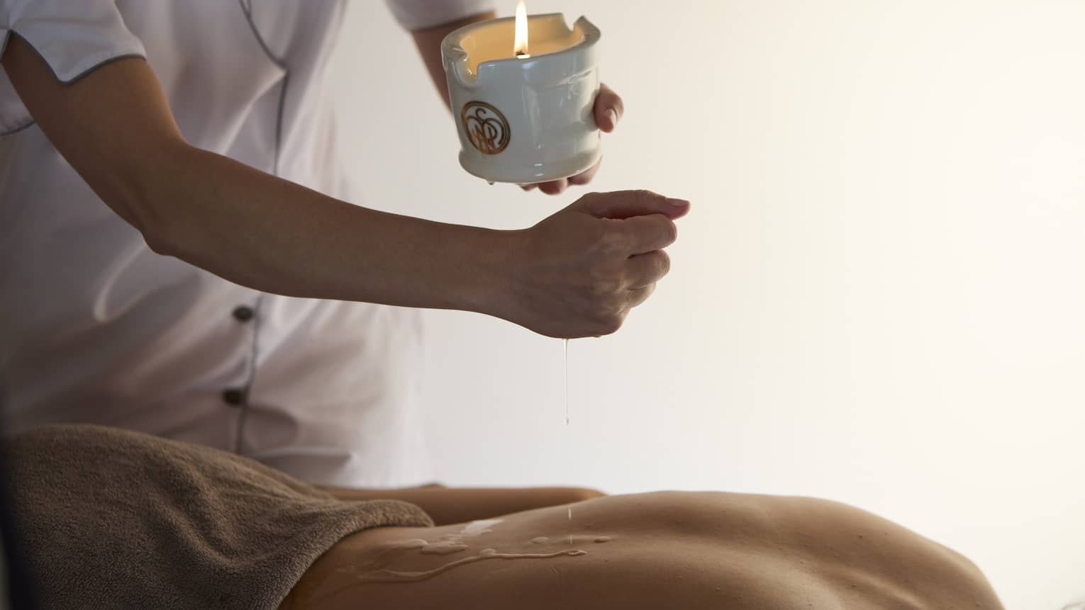 A massage therapist applies a treatment using warm wax to a person's back.