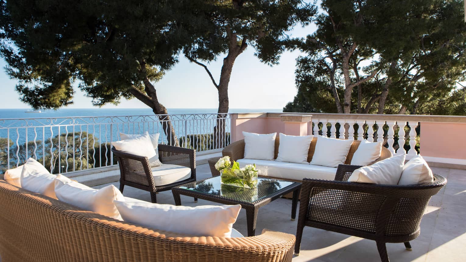 Plush patio sofas, chairs on veranda by trees, Mediterranean Sea views