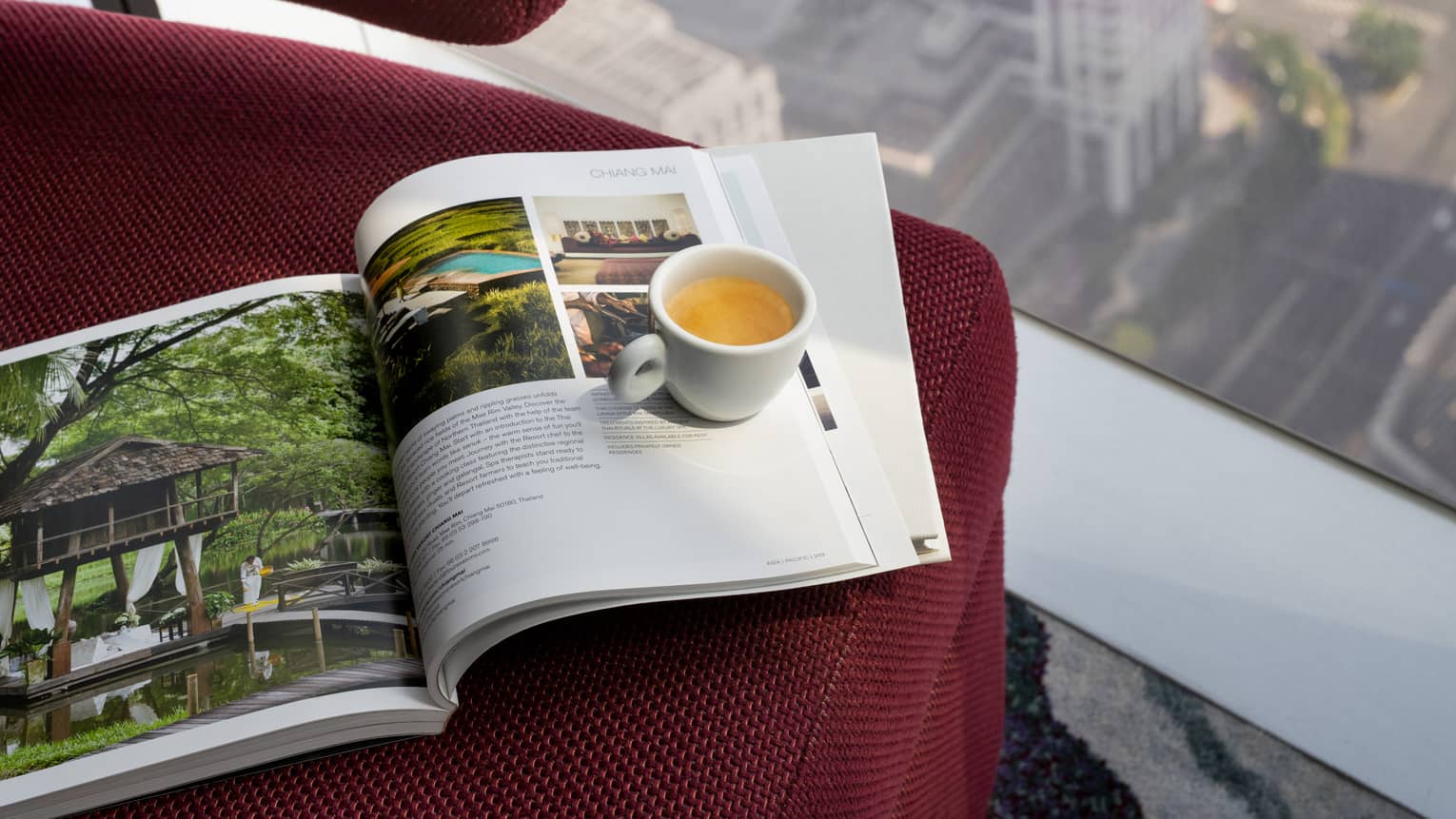 Four Seasons magazine and mug of tea sit on red chair at window