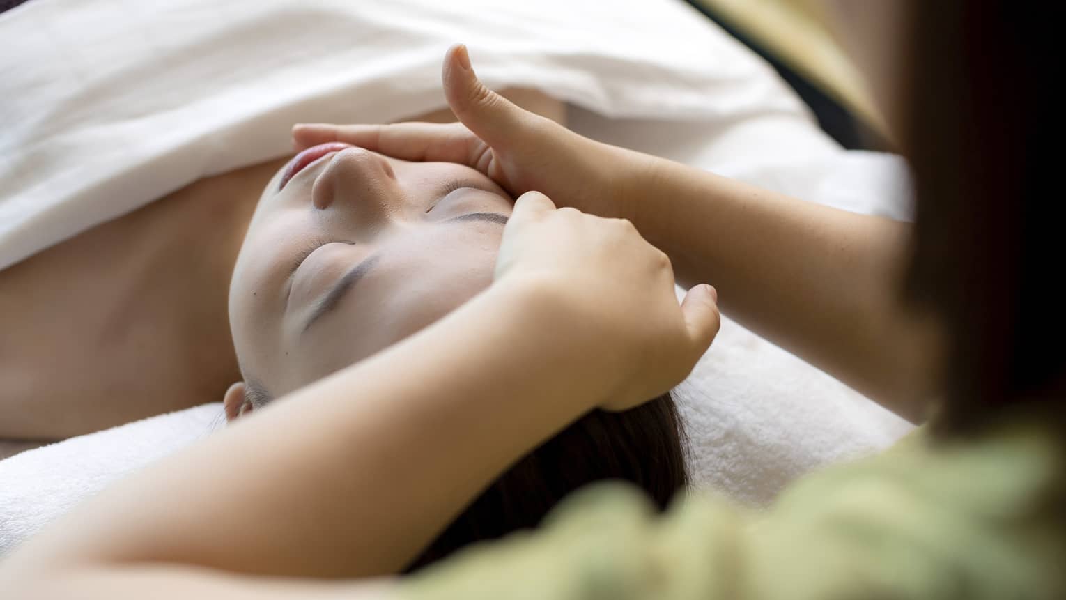 Hua Spa staff massages woman's face as she lays on treatment table