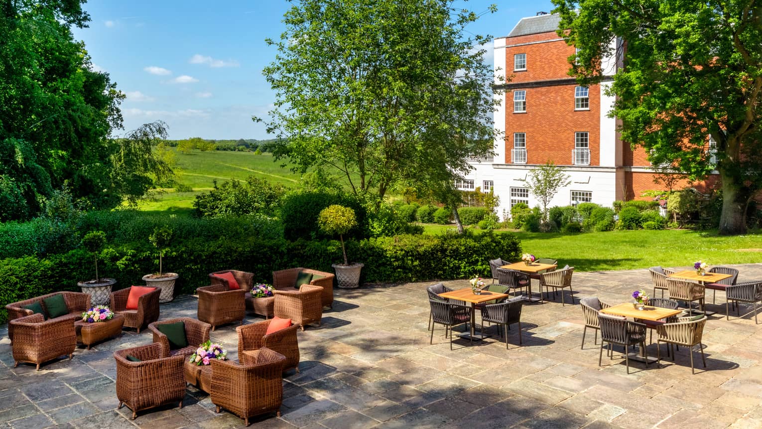 Tile-floored outdoor patio with clusters of tables and chairs, views of rolling green hills