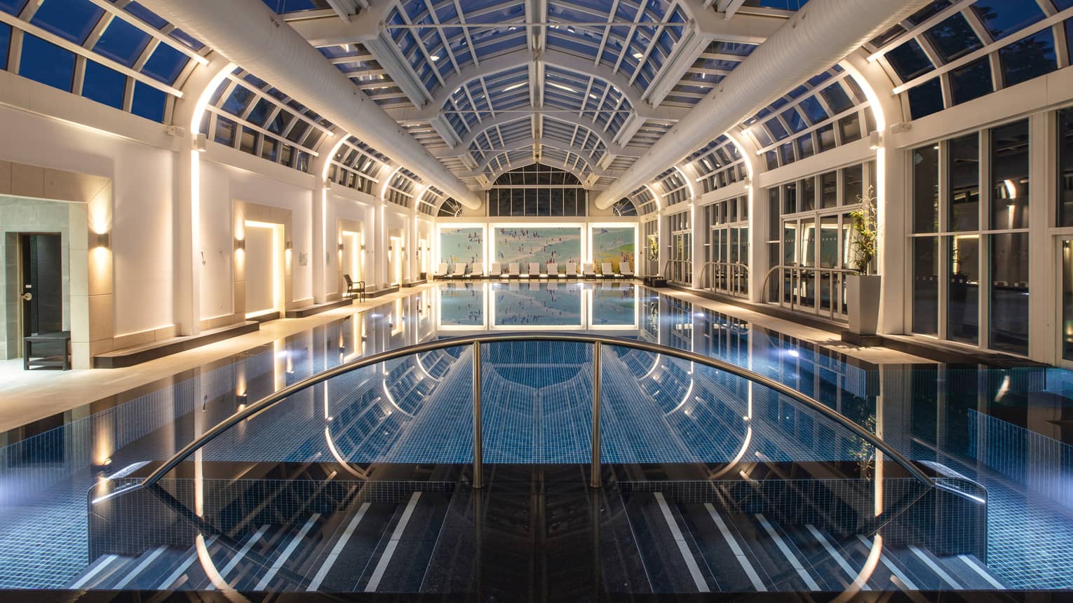 Deep blue indoor spa pool illuminated under skylight night view