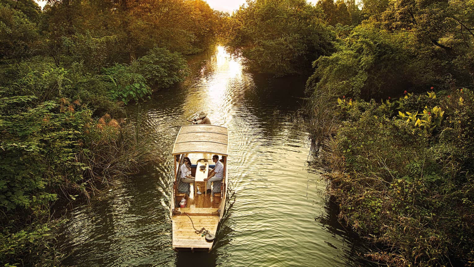 Couple in Chinese wooden row boat travelling through West Lake marsh