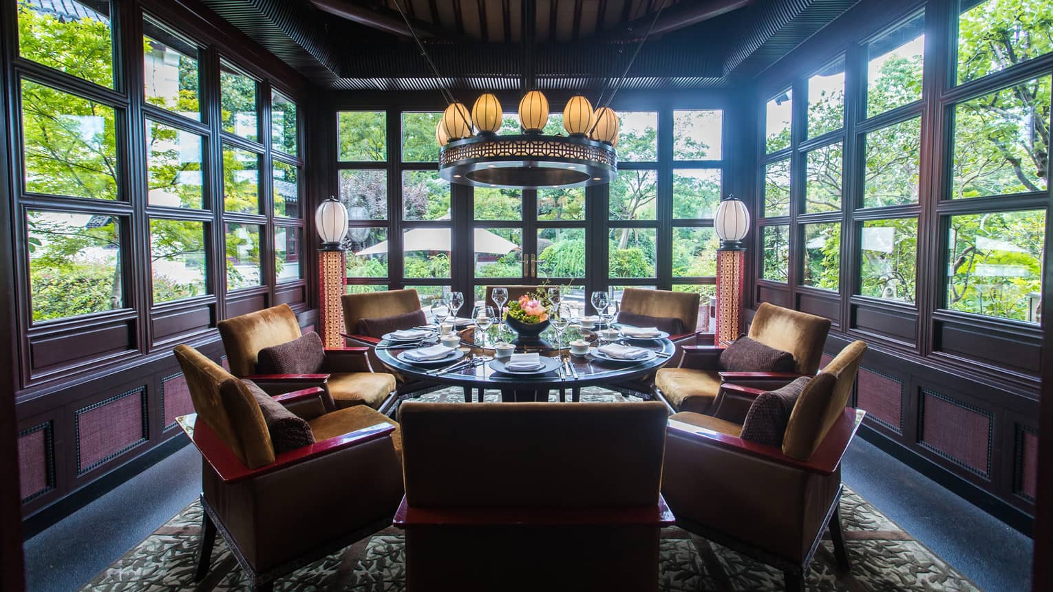 Gold velvet cocktail chairs around table in restaurant alcove lined with windows