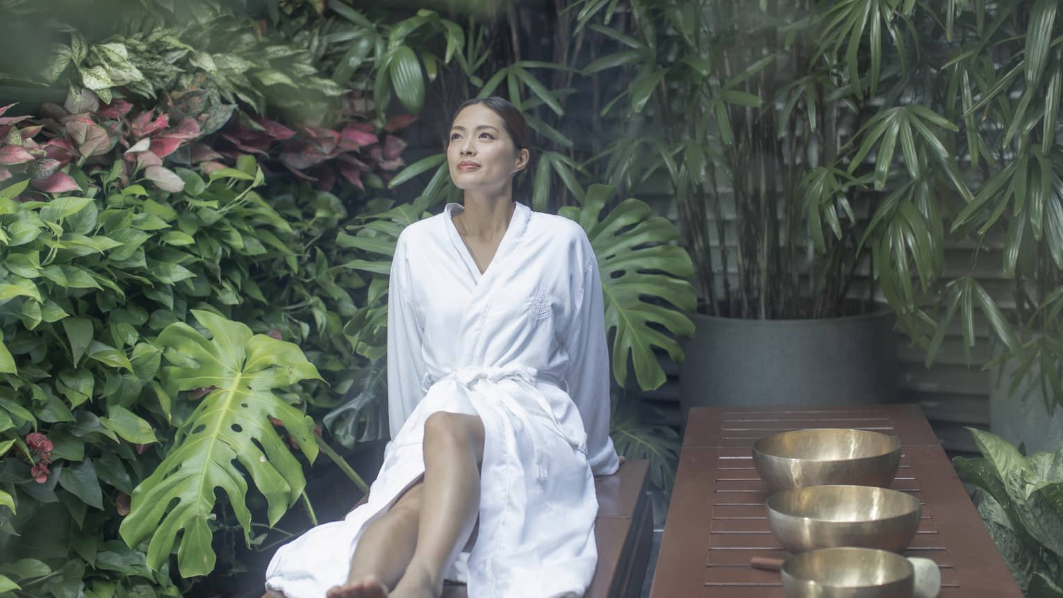 Woman wearing spa robe sits in garden