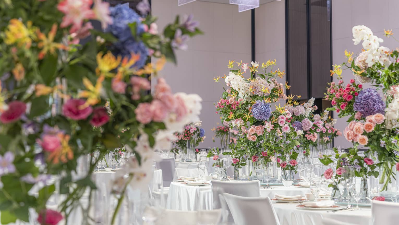 Hotel ballroom with banquet tables featuring large colourful floral arrangements