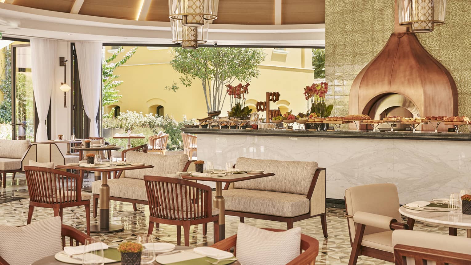 A dining outlet with a large counter area with many small tables near it.