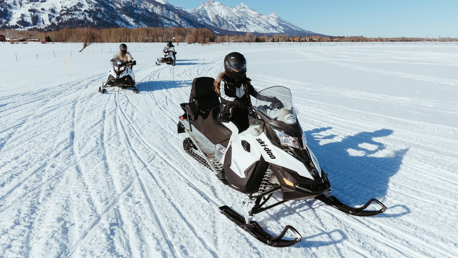 Three people on snowbmobiles.