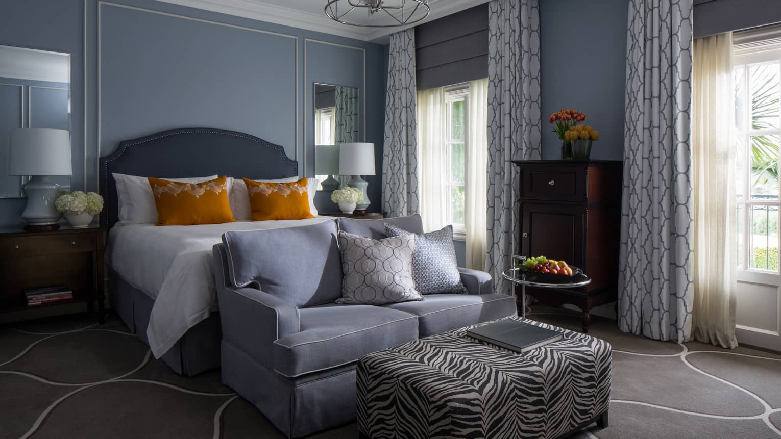 Garden-View Deluxe Room blue loveseat, zebra-print ottoman, bed with orange accent pillows