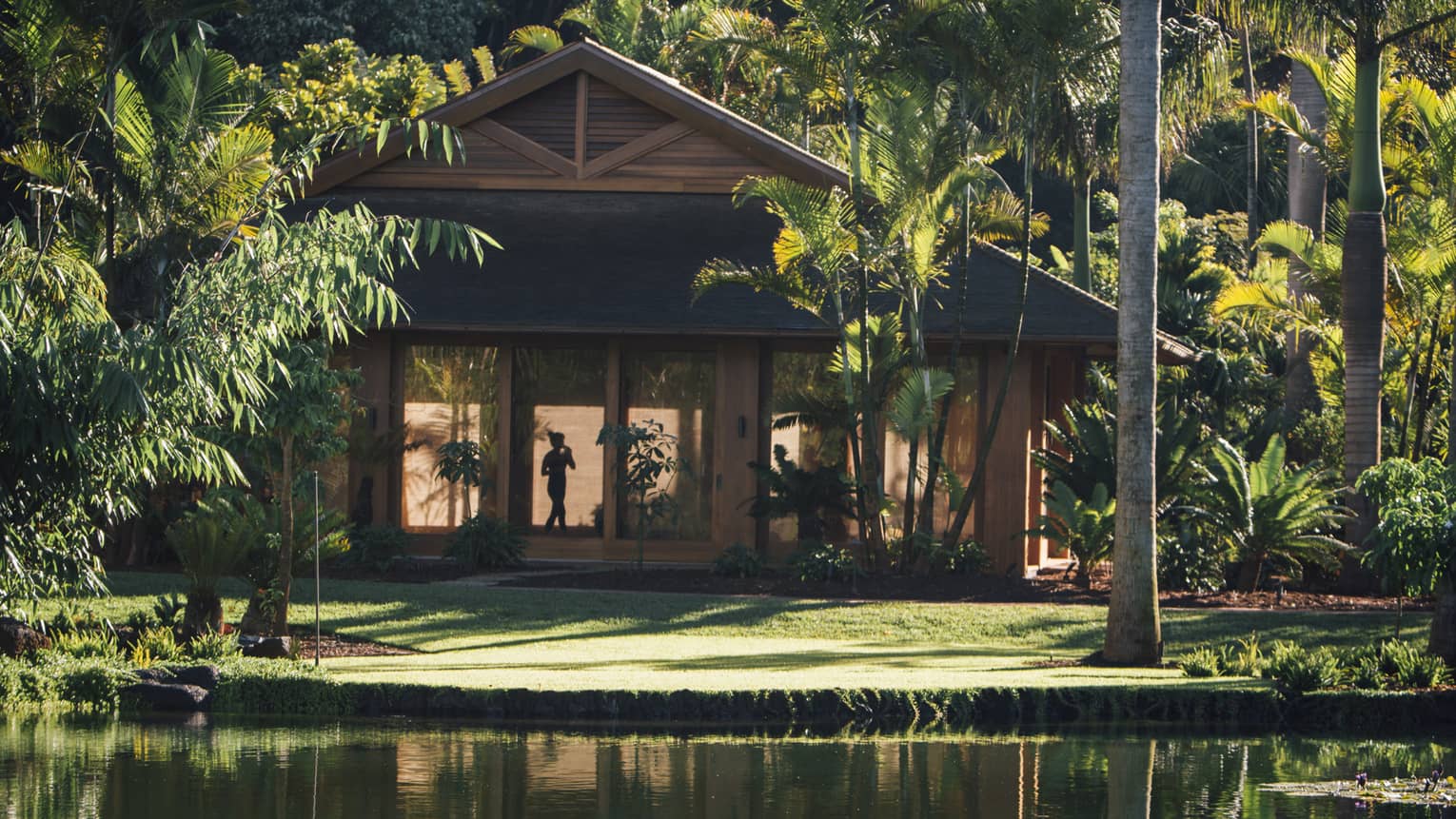 Exterior of a wooden tropical resort building by pond