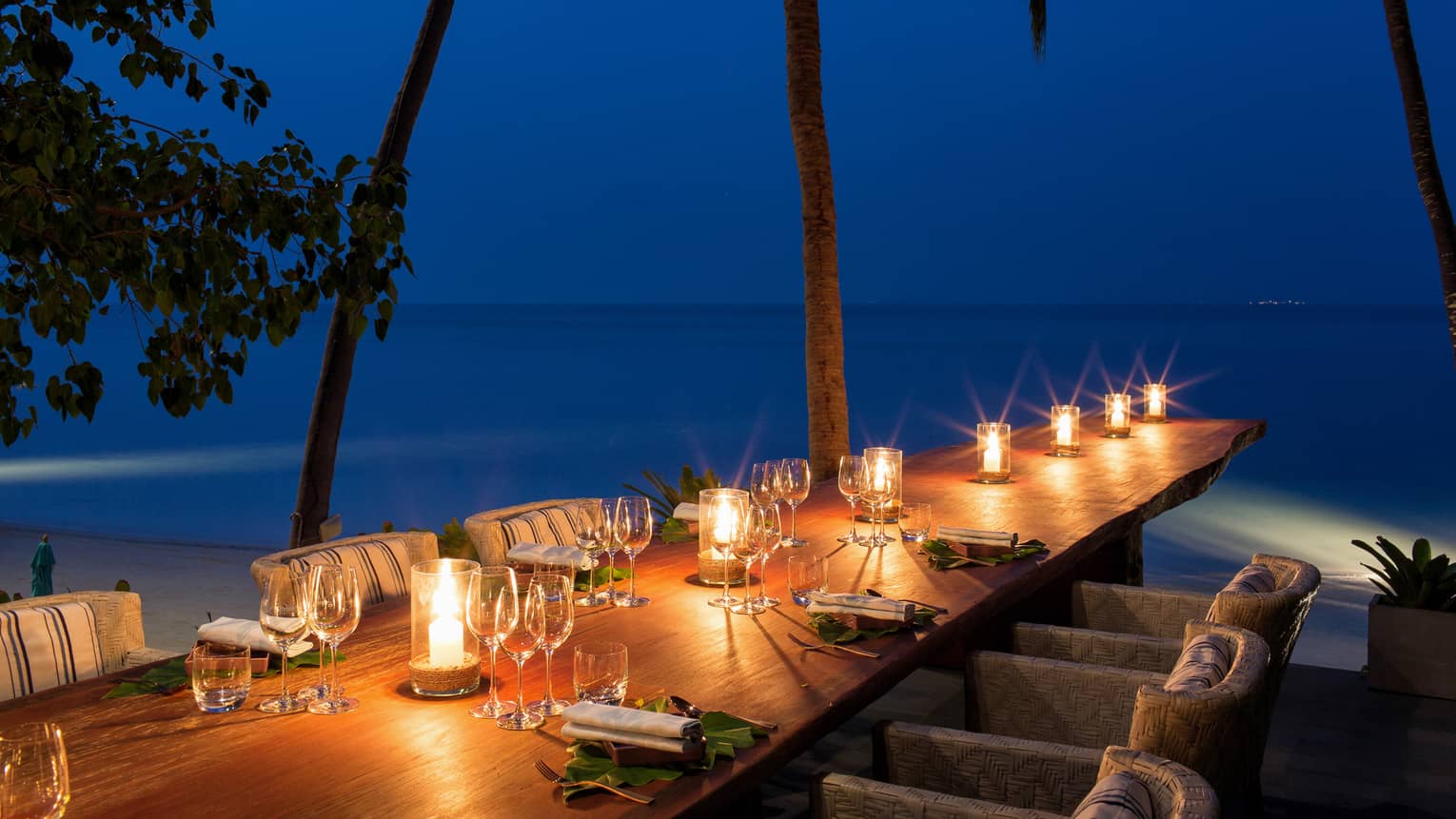 Table adorned with wine glasses and glowing candles with a view of the Gulf of Thailand,Table adorned with wine glasses and glowing candles with a view of the Gulf of Thailand