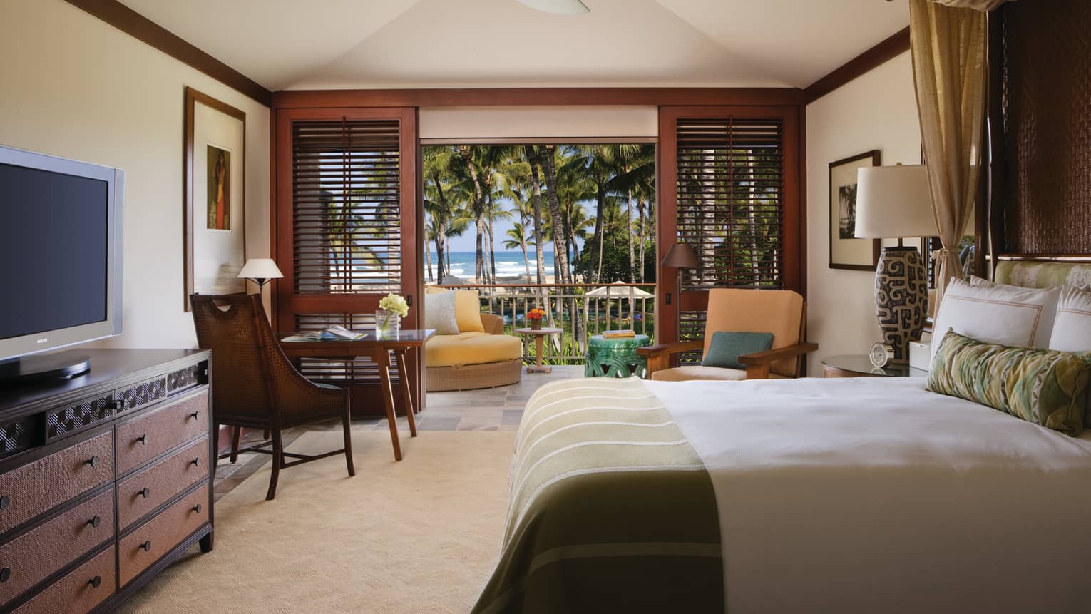 Milo Suite bed across from dresser, TV, desk and chair by open wood patio shutters