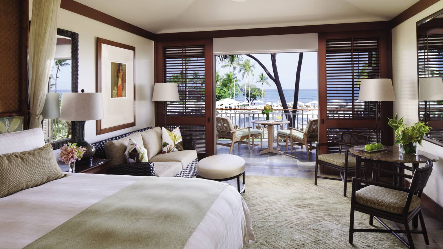 Prime Ocean-View Room bed with folded blanket, wicker loveseat, cafe table by wood patio shutters