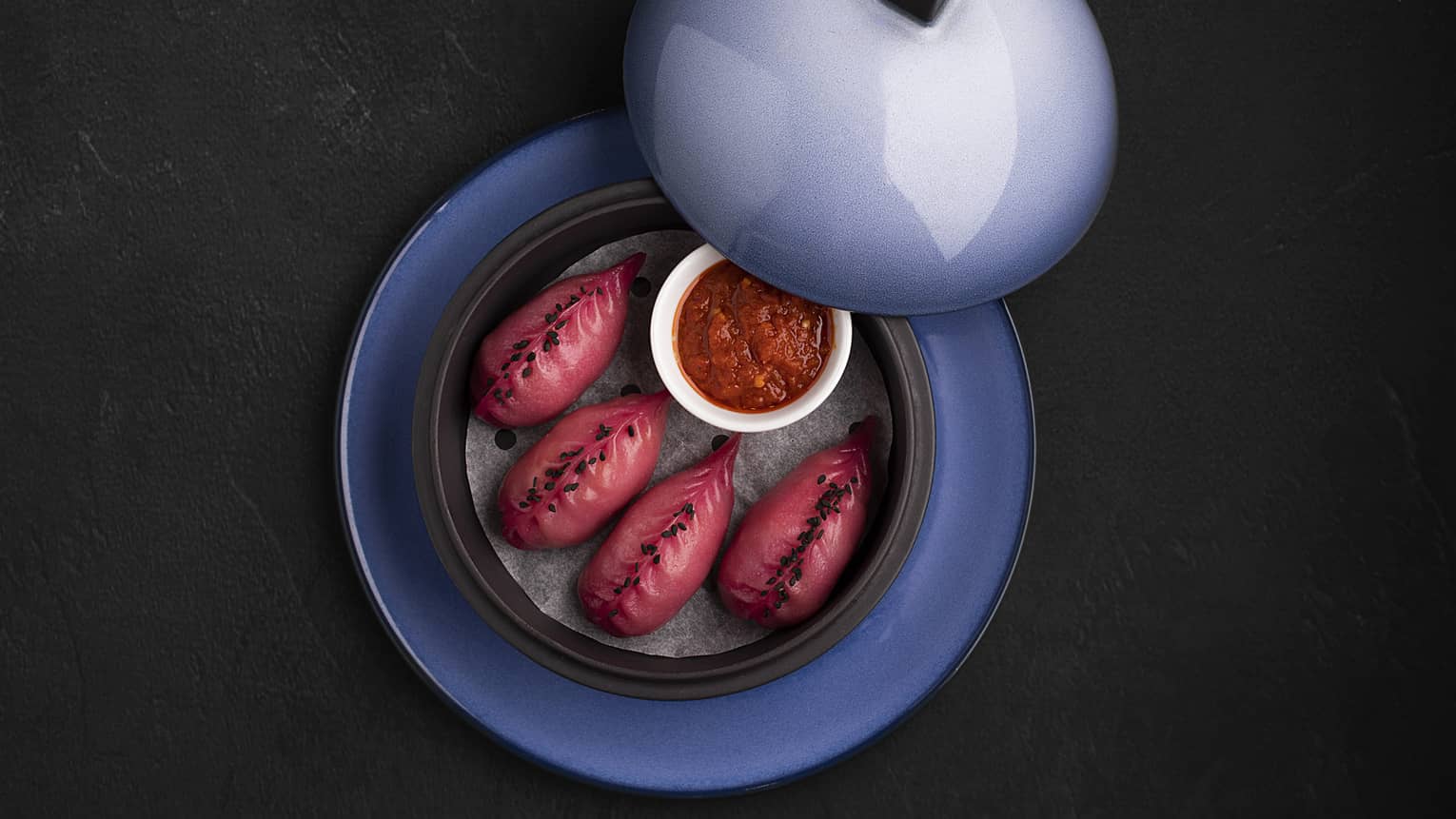 Lobster Dim Sum featuring lobster, yuzu and sambal sauce served in a light blue plate with a lid